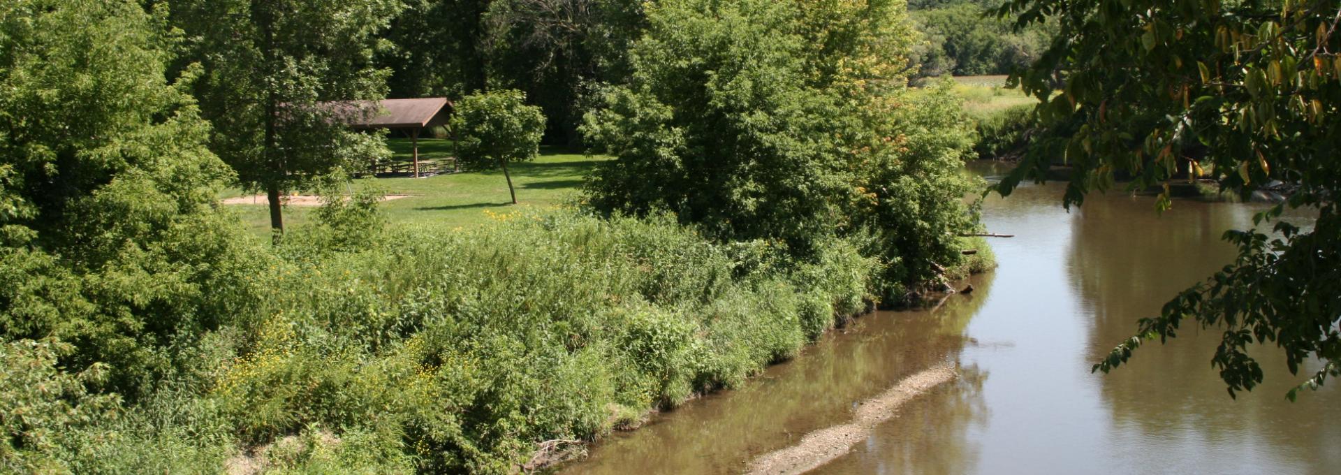 A river in the summer with a grassy area for recreational activities