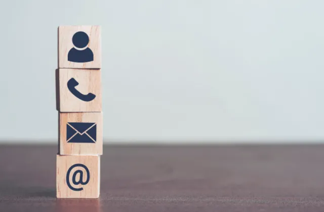 wooden blocks stacked up on each other with symbols of contacts. 