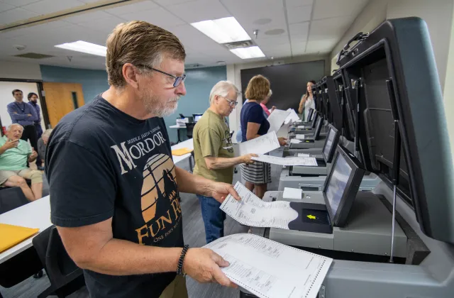 People putting test ballots into tabulators