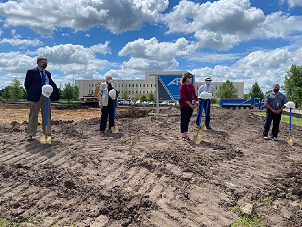 Five people standing spaced out in front of shovels at the groundbreaking event for the southeast regional crisis center