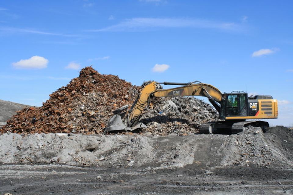An excavator uses a magnet to pull ferrous metals from the ash at the Kalmar Landfill