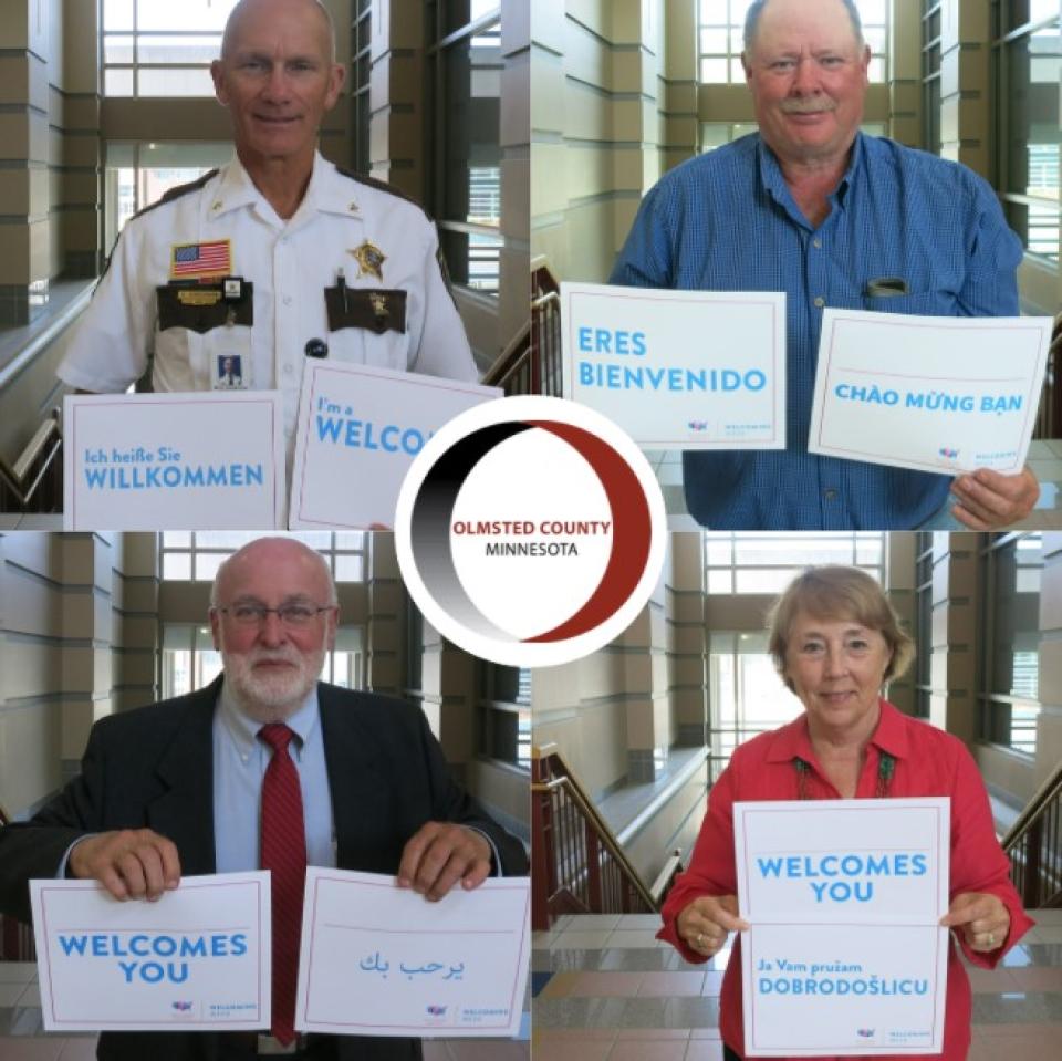 Welcoming Week 2021 - Pictures of Olmsted County Commissioners and sheriff holding Welcoming Week signs