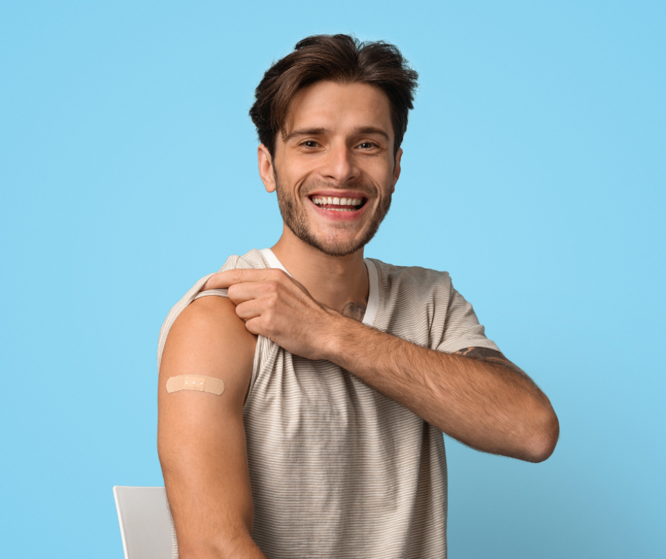 A man holding up his sleeve with a band aid on his arm.