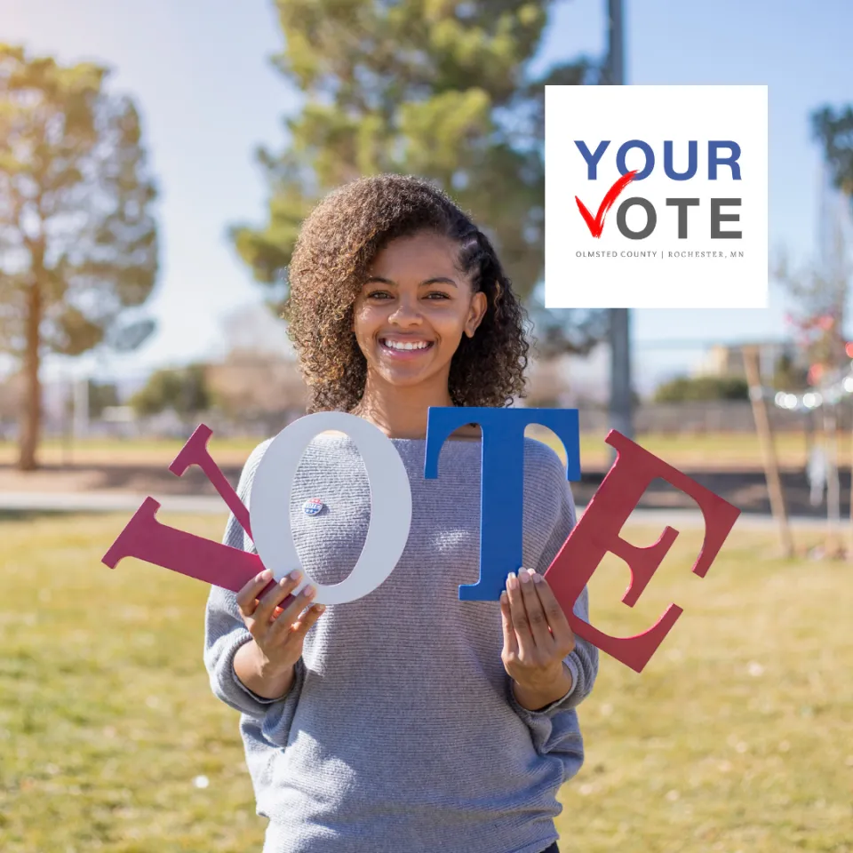 A person holding the letters V.O.T.E with the Your Vote logo in the upper right-hand corner.