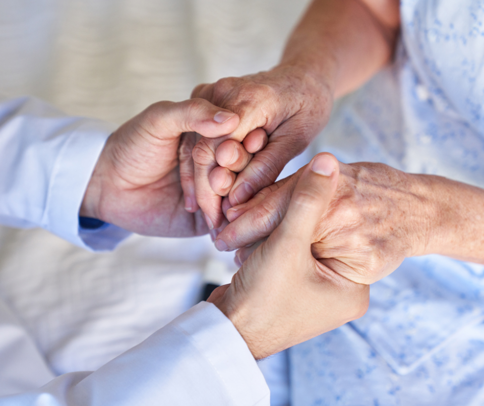 A senior citizen holding hands with another person.