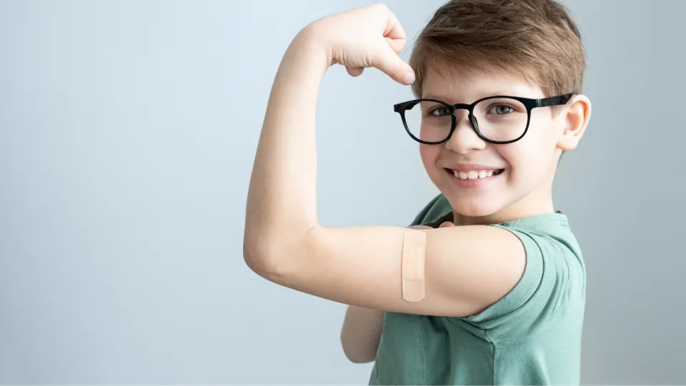 Young boy with band aid where he got a vaccine.