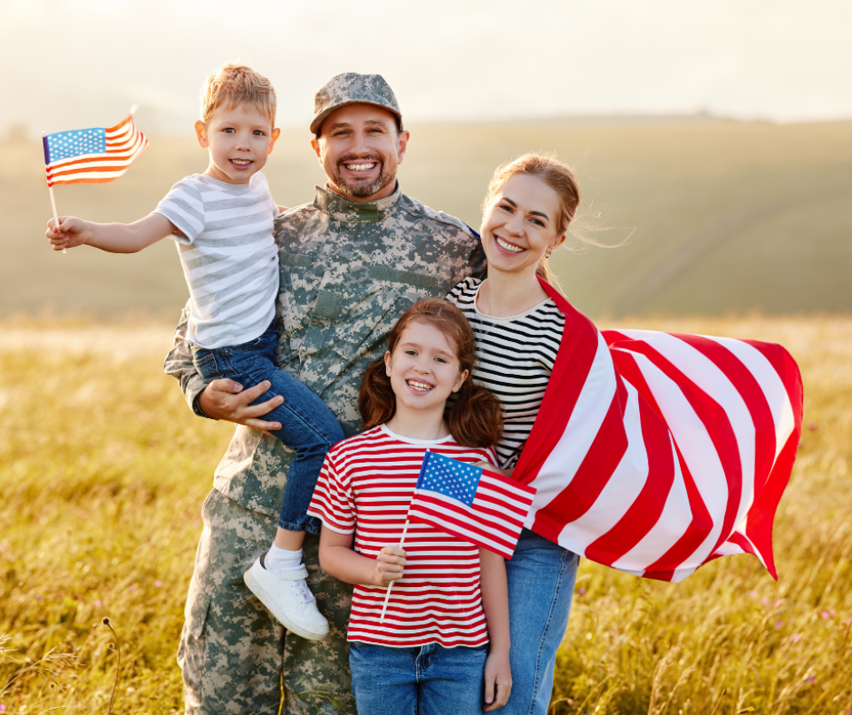 A veteran with their family. Family members are holding American flags.