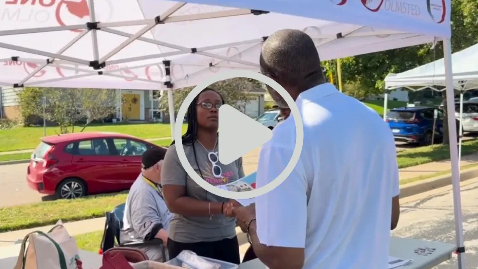 MOVE member and community member talking on at booth with the YouTube play button overlaying the image