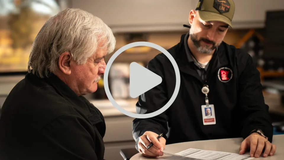 Veteran Services staff member working with veteran with YouTube play button overlayed