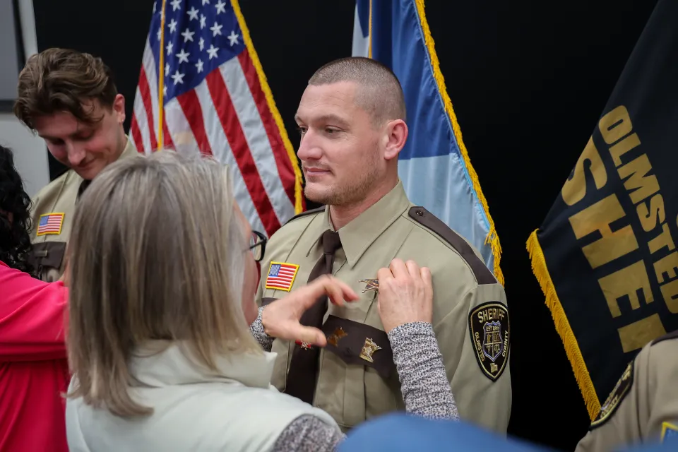 Family member or friend pinning the badge on new hire's uniform