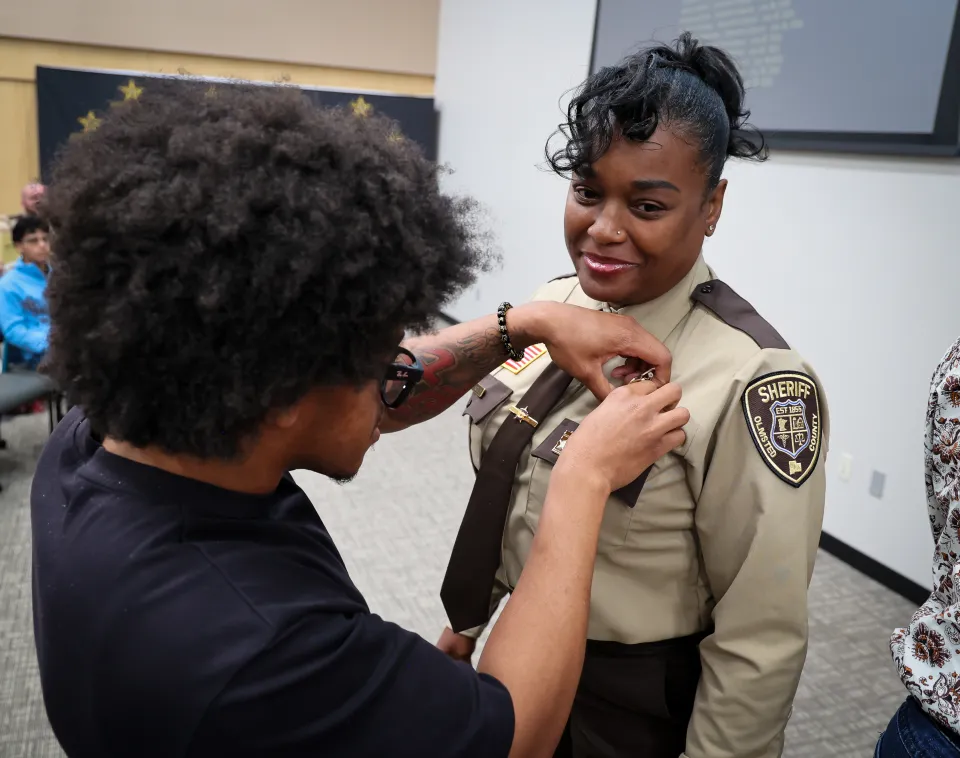 Family member or friend pinning the badge on new hire's uniform