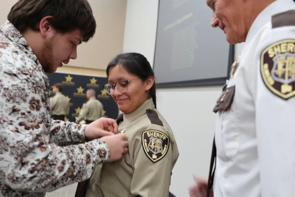 Family member or friend pinning the badge on new hire's uniform