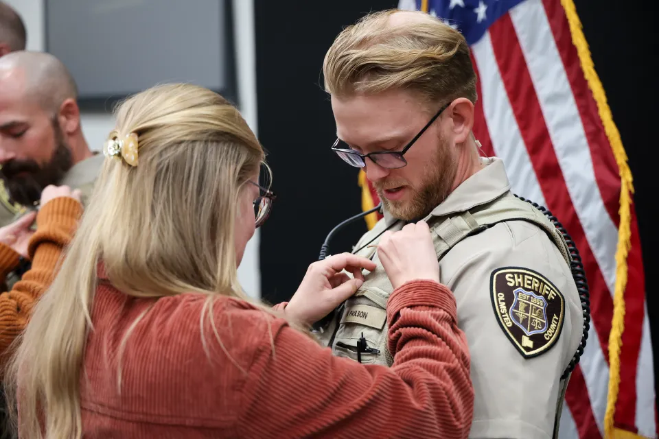 Family member or friend pinning the badge on new hire's uniform