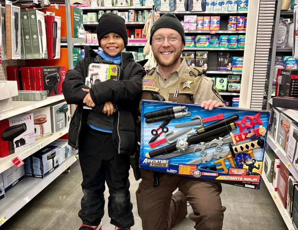Deputy Jacobson poses with a child at Shop with a Cop in 2025