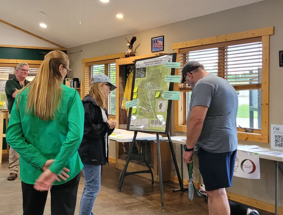 People standing around a map at an open house for Parks and Trails community engagement