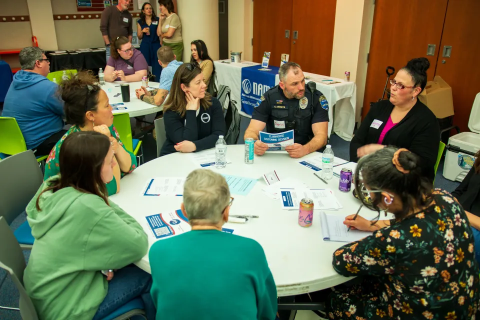 A group of people sit around a table having a discussion.