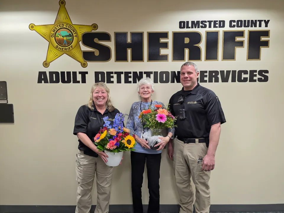 Members of the Sheriff's Office give flowers to a volunteer inside the Adult Detention Center following her retirement