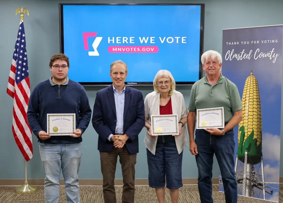 William Harvey, Marlys Ohnstad, Kenneth Schultz, and Minnesota Secretary Steve Simon standing with awards