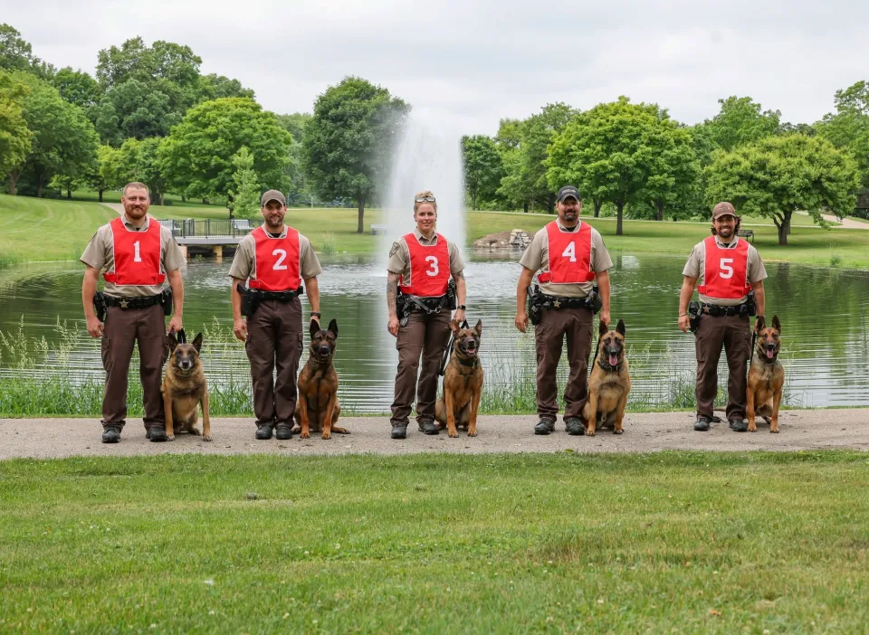 Sheriff's Office K9 team with dogs stand in front of a pond.