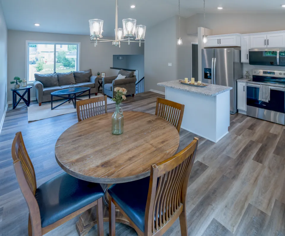 Dining area of a housing development in the foreground. The living room and kitchen are in the background 