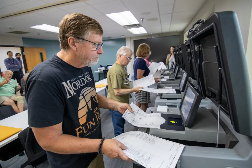 People putting test ballots into tabulators