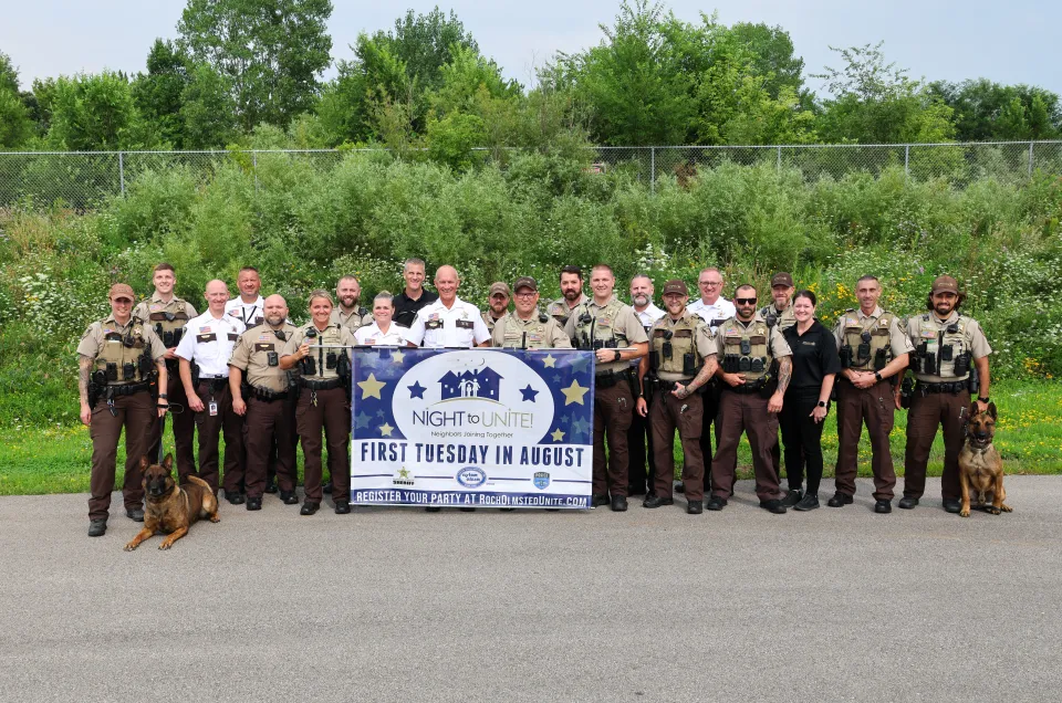 Sheriff's Office staff pose for a photo with the Night to Unite banner prior to attending parties throughout Olmsted County.