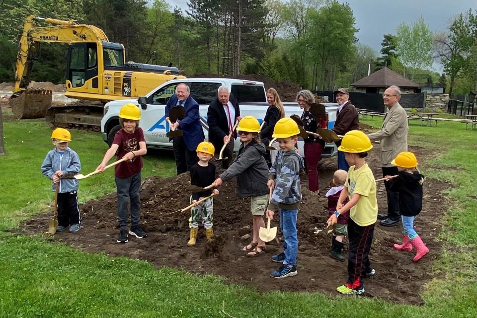 Adults and children shoveling dirt at the Oxbow Park nature center groundbreaking ceremony