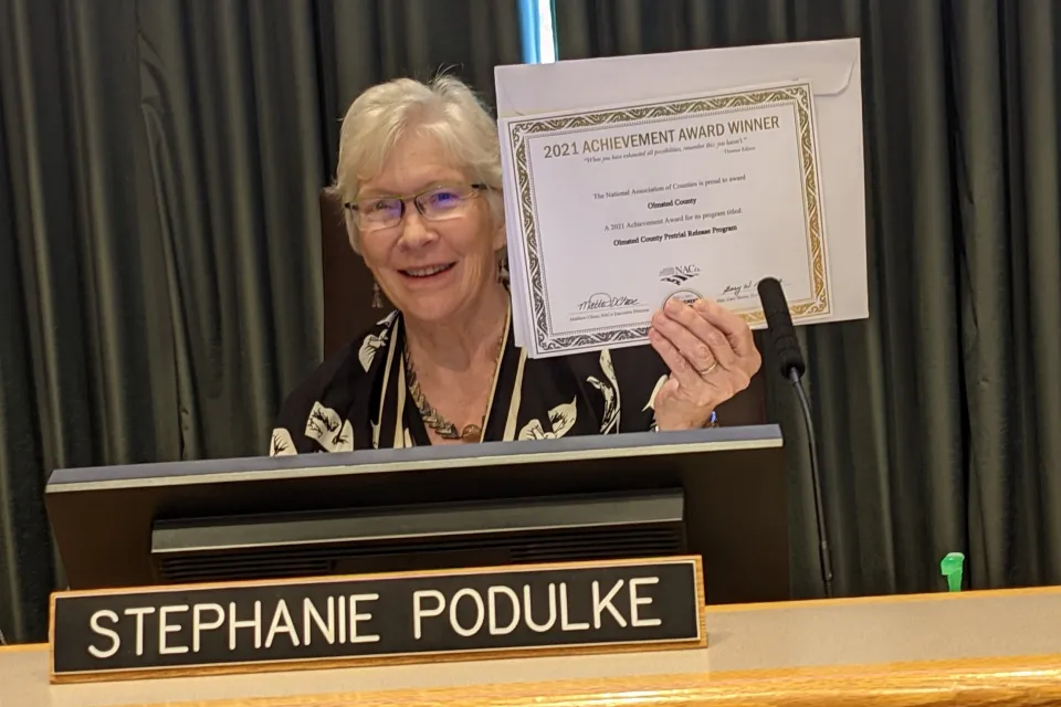 Commissioner Podulke holding our 2021 NACo Achievement Award