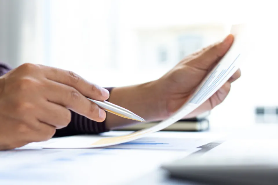 Hand holding pen, reviewing paperwork