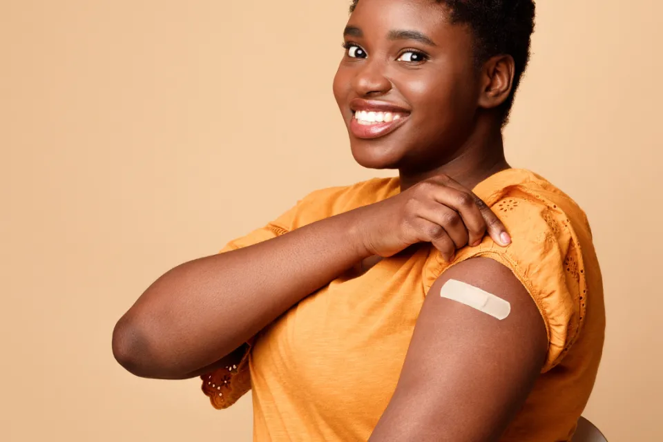 Person rolling their sleeve up to show a band-aid on their arm.