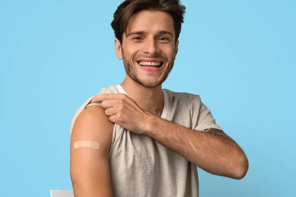 A man holding up his sleeve with a band aid on his arm.