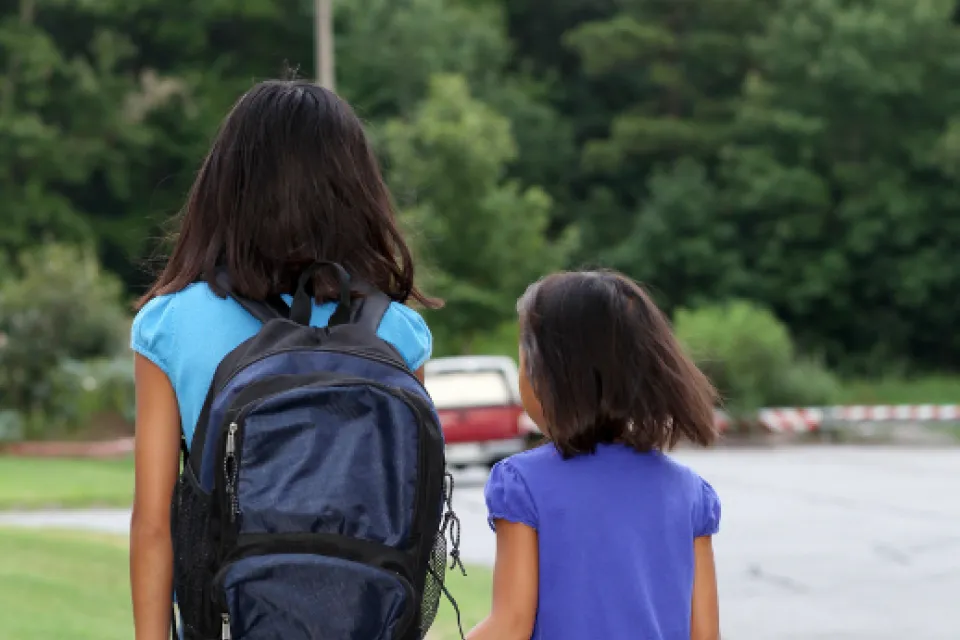 Two children walking on a sidewalk