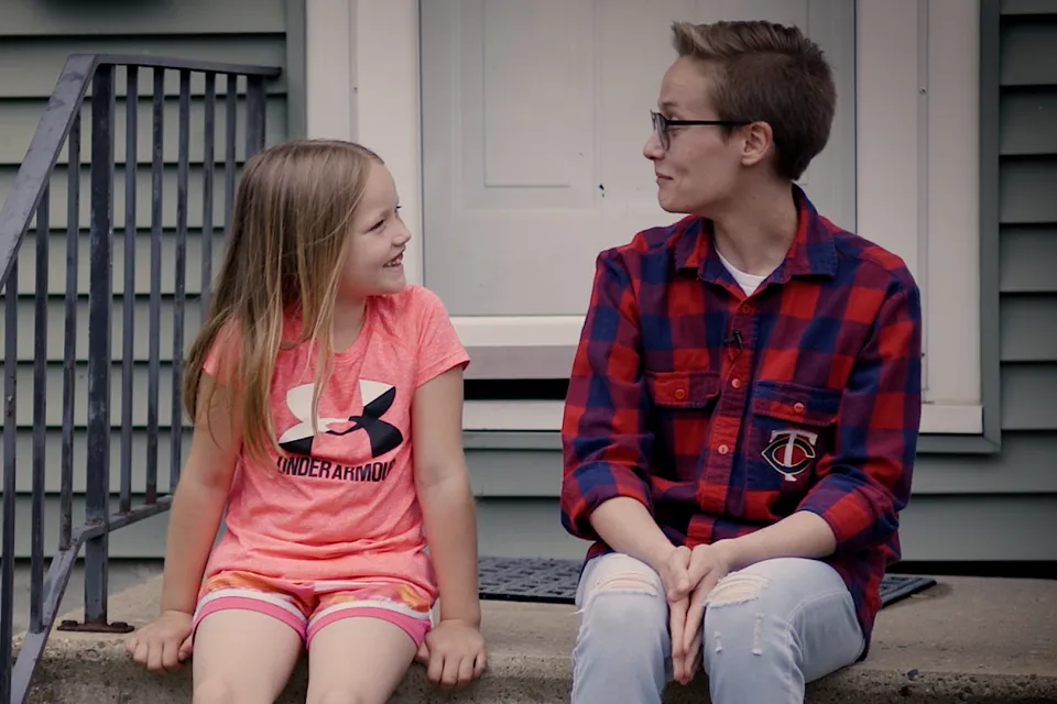 Adrian and their daughter sitting on a step.