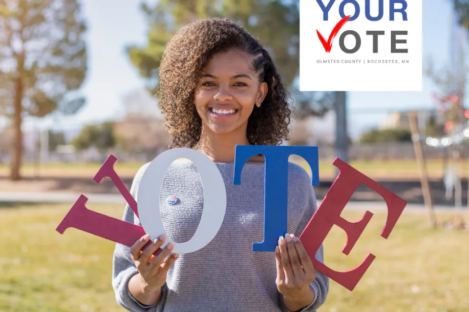 A person holding the letters V.O.T.E with the Your Vote logo in the upper right-hand corner.