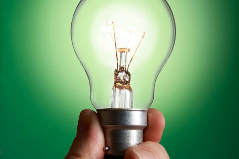 A hand holding a green light bulb