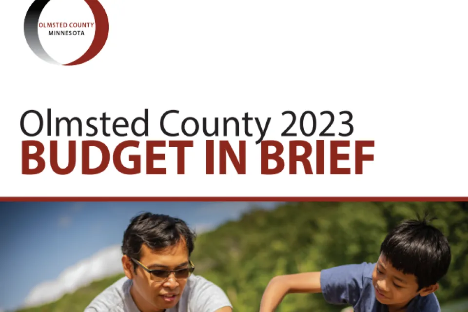 Front page of the 2023 Olmsted County Budget in Brief. Features a man and children playing in the sand at the Chester Woods beach.