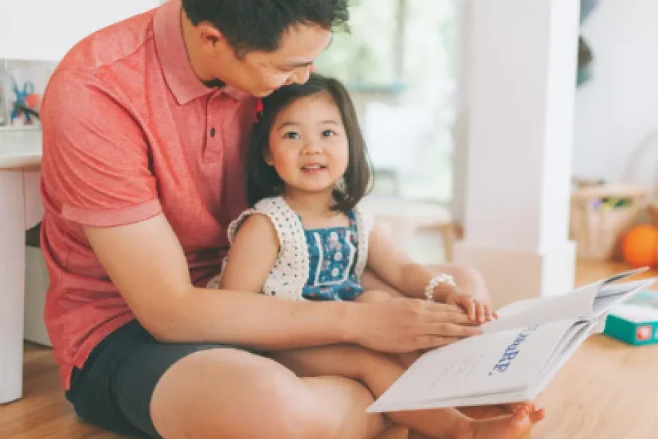 Father reading book to young daughter