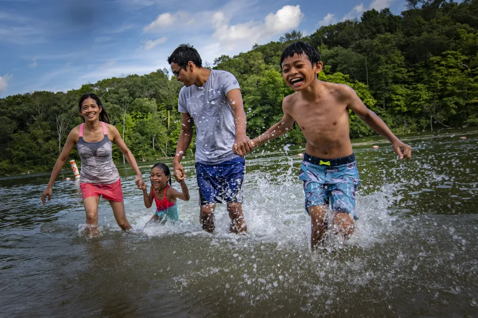 Family of 4 splashing in the water at Chester Woods Beach