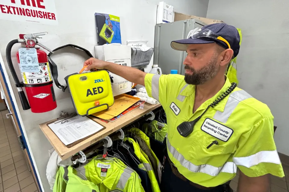 Waste Abatement Supervisor Khalid Alasadi picks up the AED machine at the Recycling Center Plus.