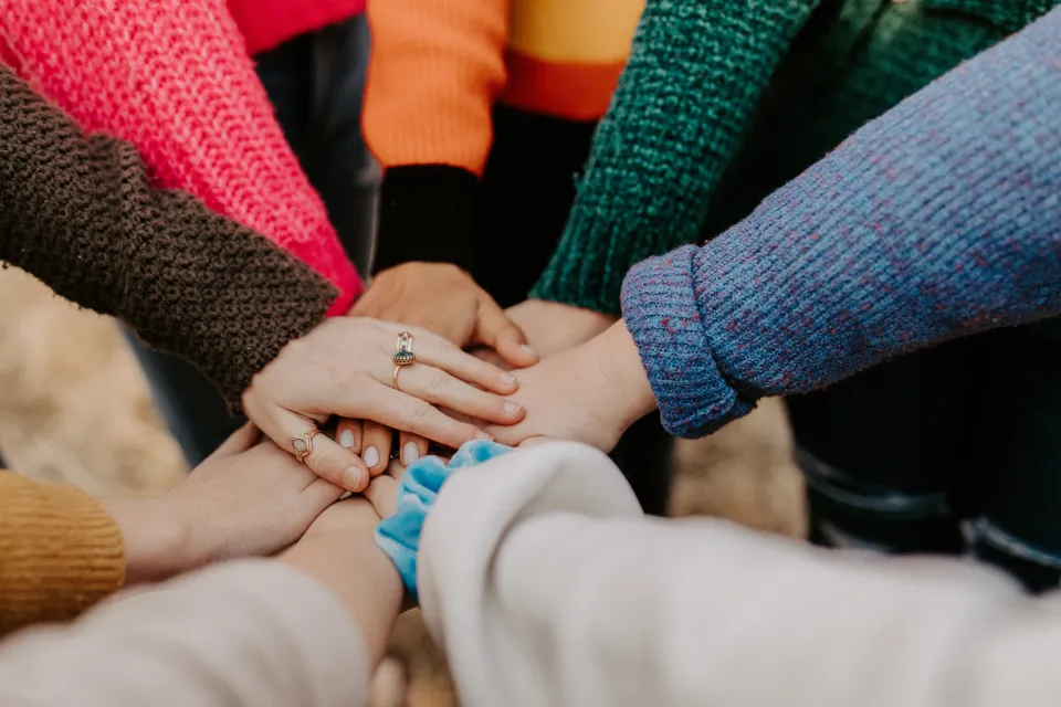many people putting their hands in the middle of a circle