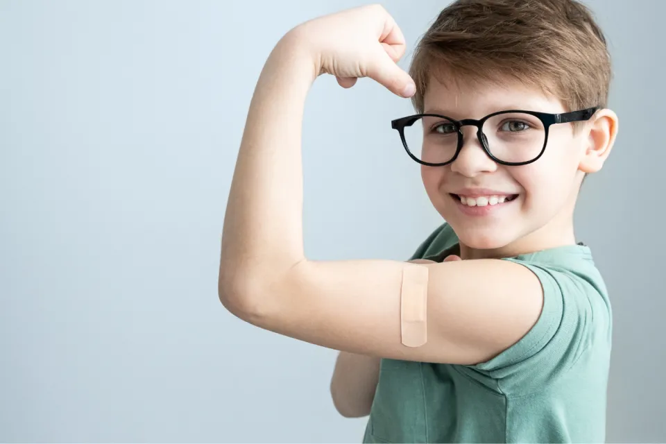 Young boy with band aid where he got a vaccine.
