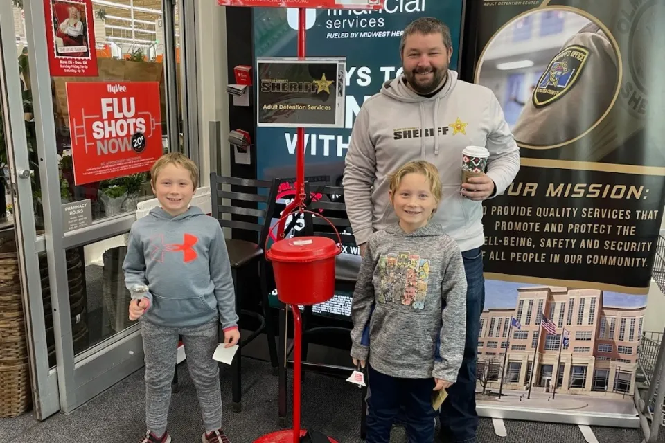 Staff member and family ring bells for the Salvation Army at Hyvee