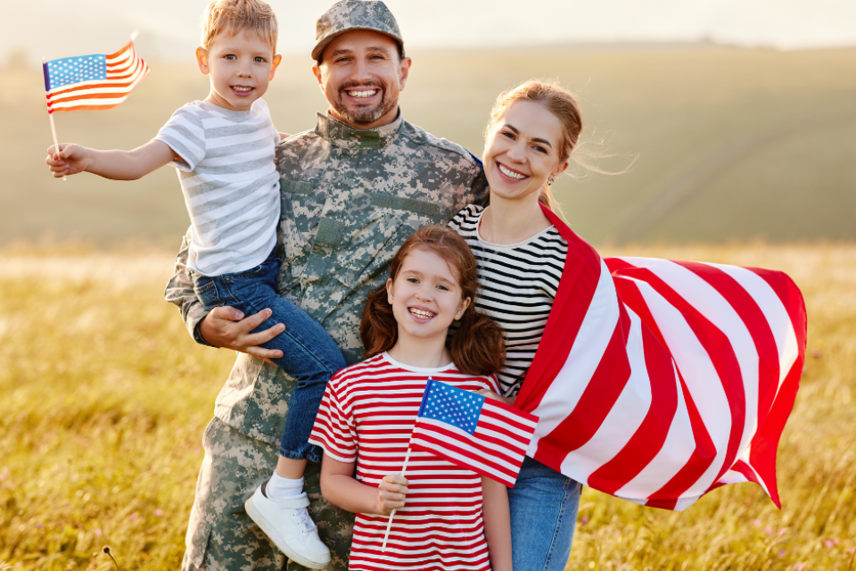 A veteran with their family. Family members are holding American flags.