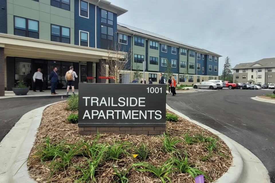 A sign for Trailside Apartments with the building in the background