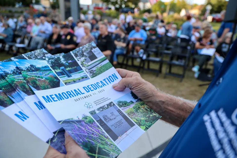 Person holding memorial programs at the dedication. 