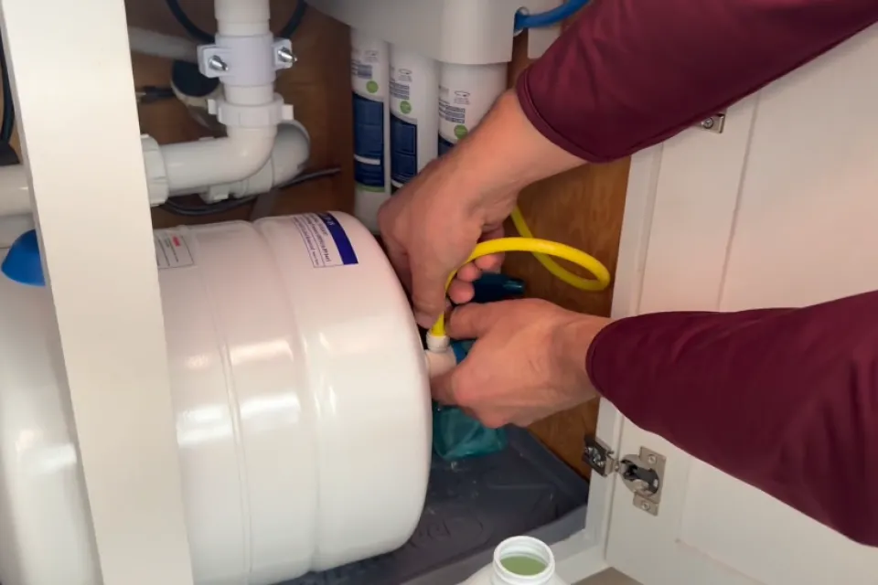 Hands working under sink with RO system