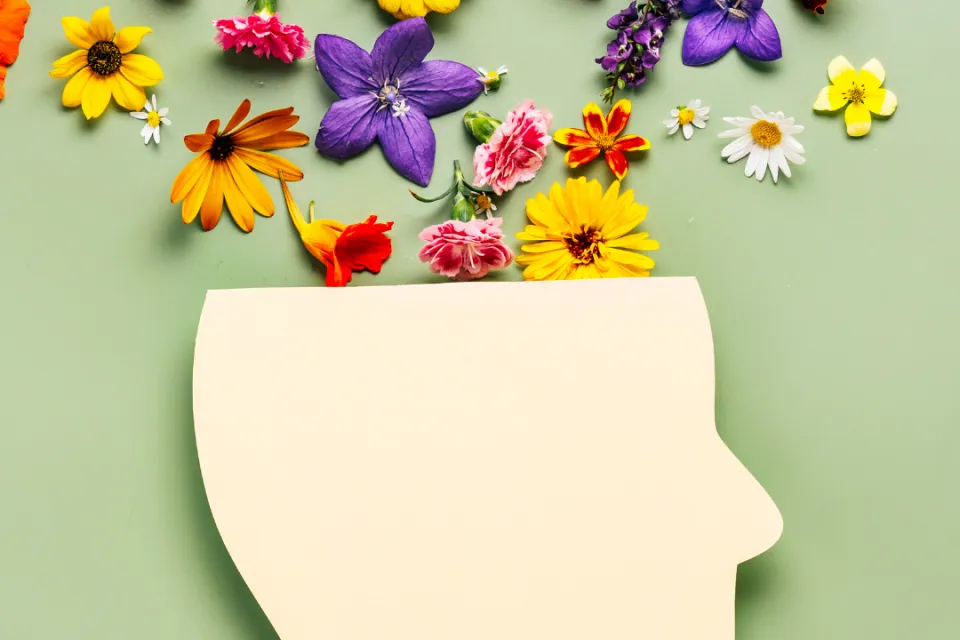 Paper cut human head symbol and flowers on a background