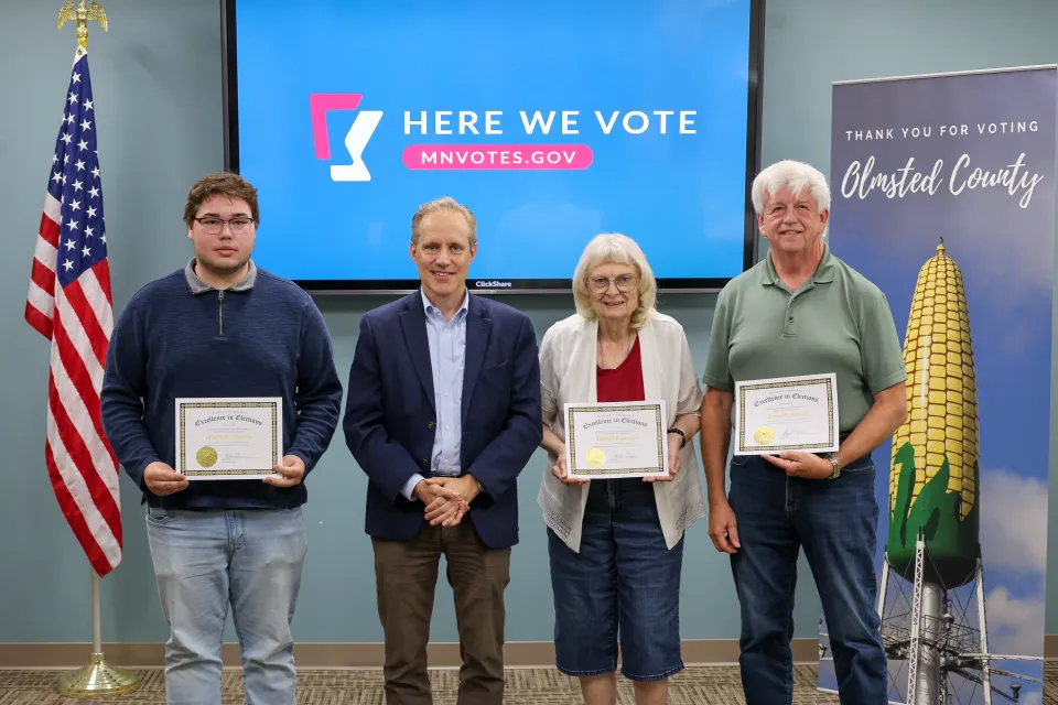 William Harvey, Marlys Ohnstad, Kenneth Schultz, and Minnesota Secretary Steve Simon standing with awards